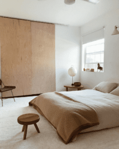 Quarto Japandi com portas de armário de madeira compensada e roupa de cama de cor clara