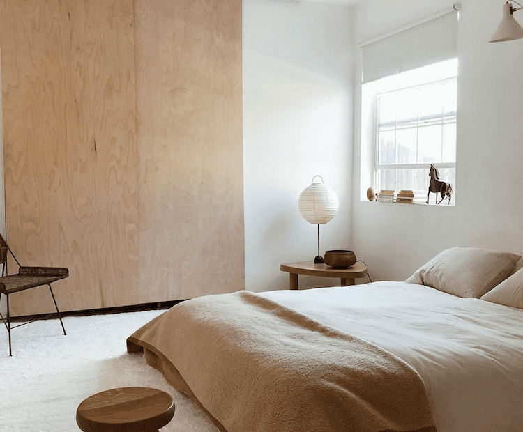 Quarto Japandi com portas de armário de madeira compensada e roupa de cama de cor clara